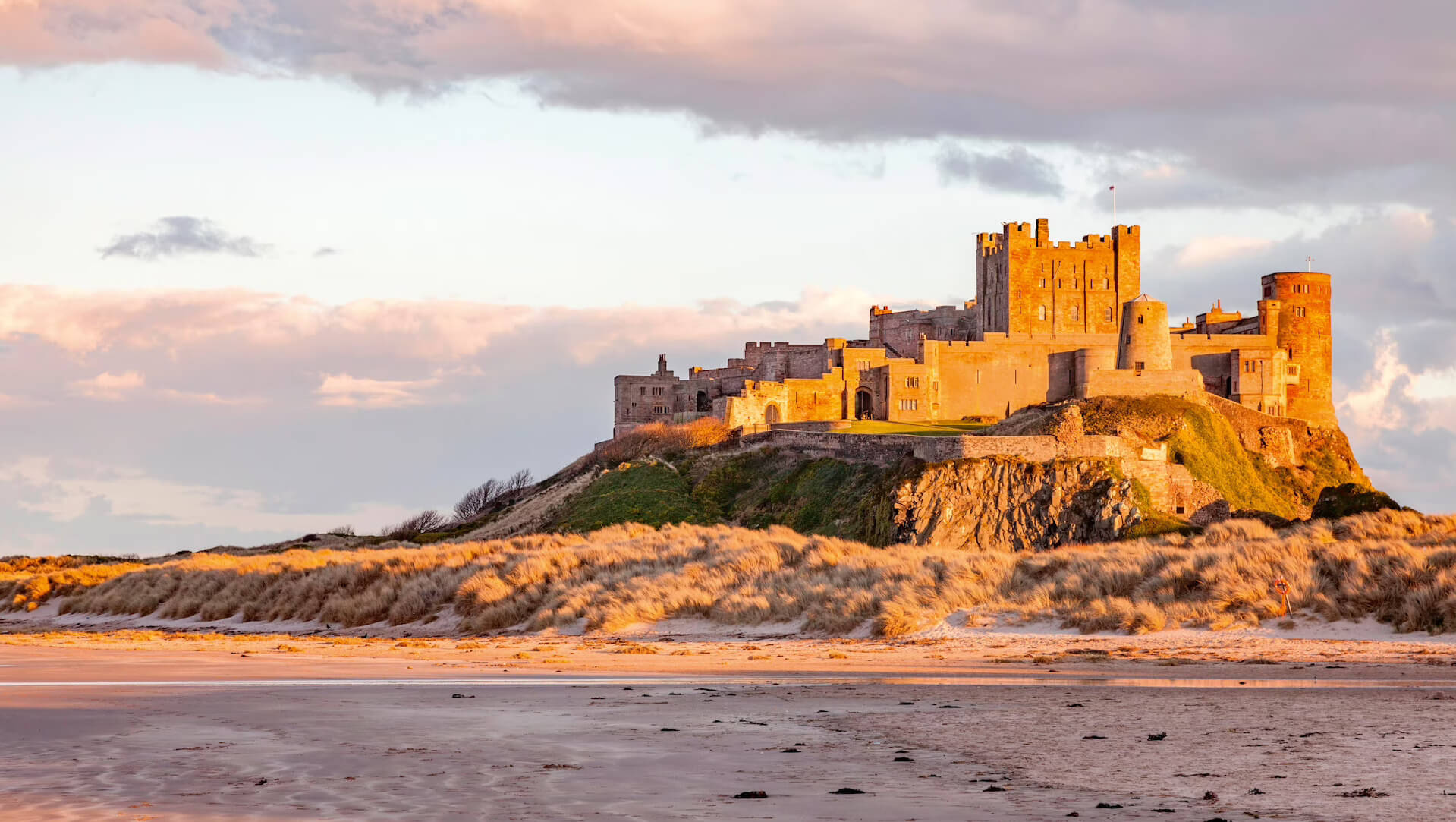 Bamburgh Castle at sunset above the beach